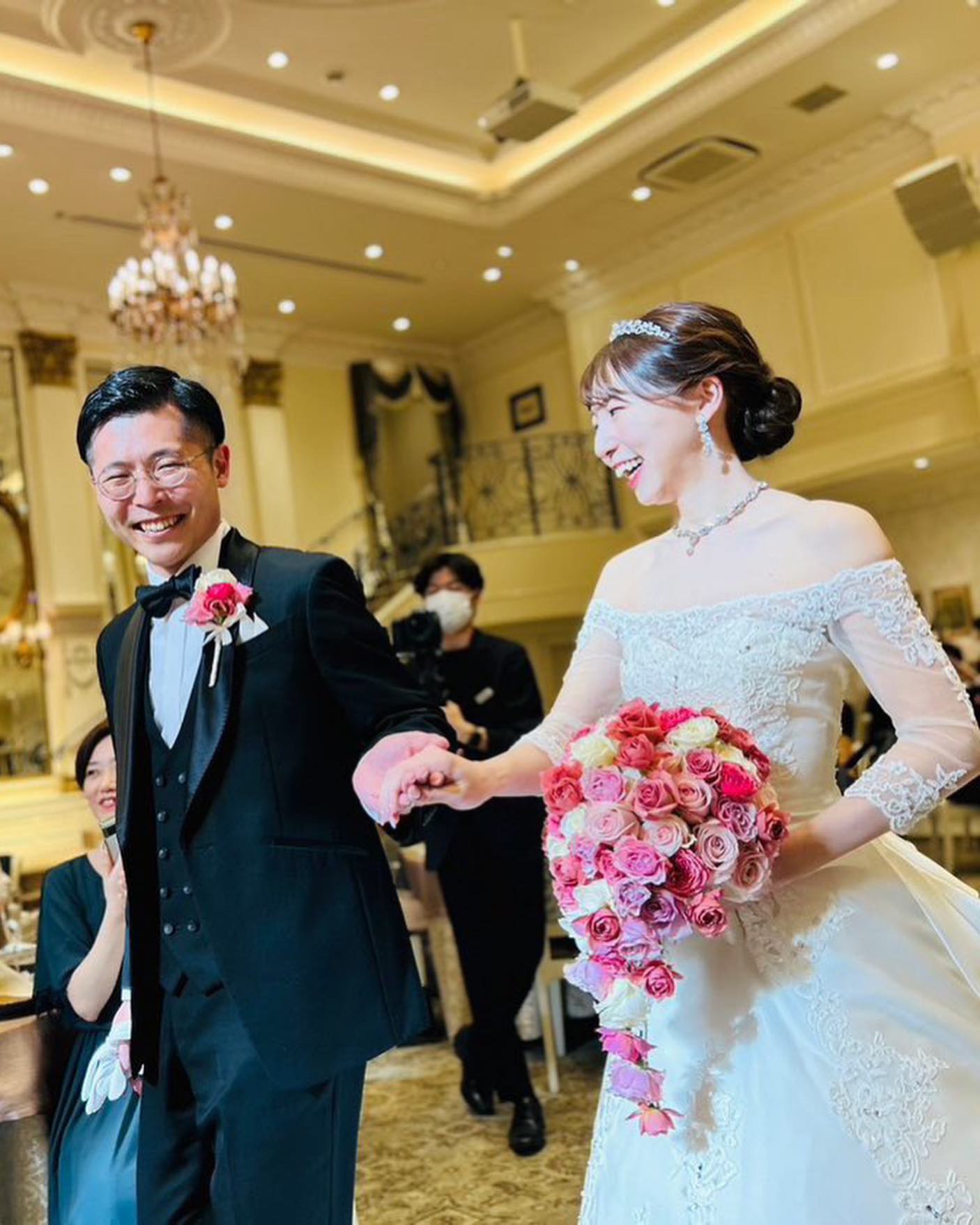 ピンクのバラのキャスケードブーケを持つ花嫁様とご新郎様。ハートコート横浜の披露宴にて