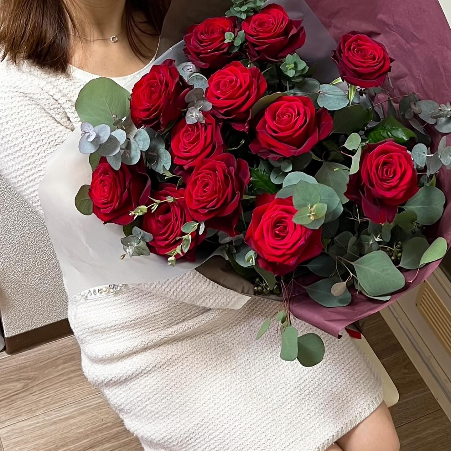 結婚記念日にご主人様から贈られた、抱えるほどの赤いバラ12本の花束を持つ卒花嫁様