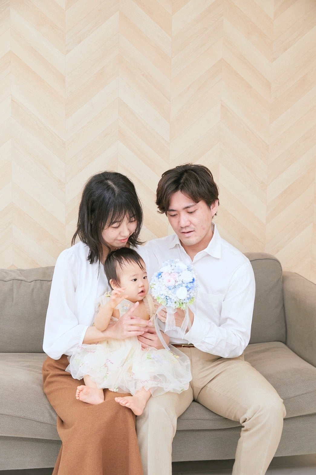 1歳の記念写真。プリザーブドフラワーのミニブーケを手にした家族3人