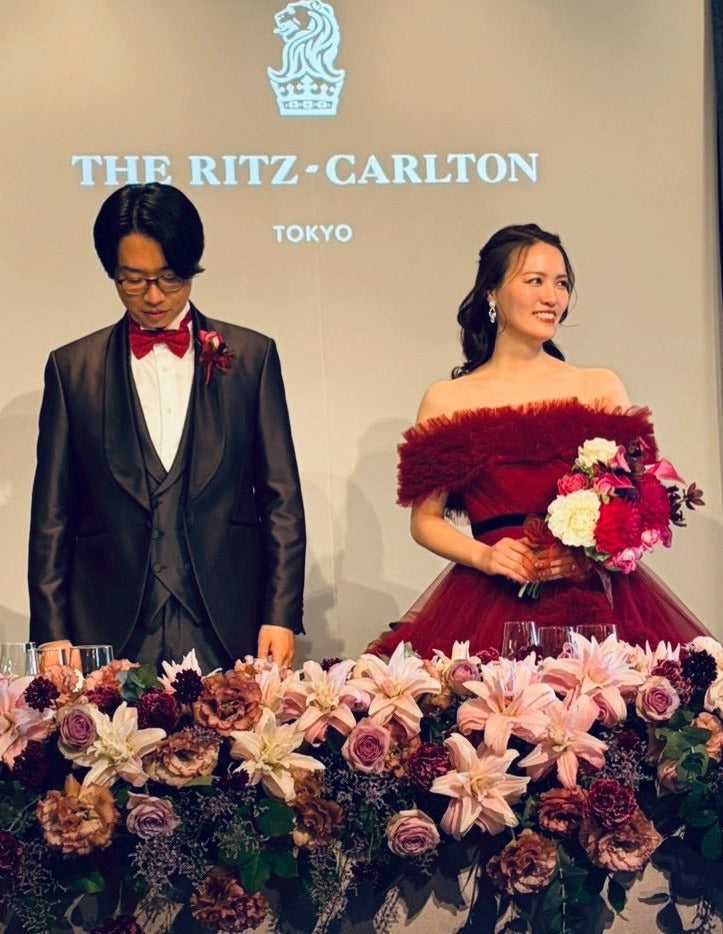 リッツ・カールトン東京のサイン前 お色直しの赤いドレスと深紅のブーケを持つ花嫁様と新郎様